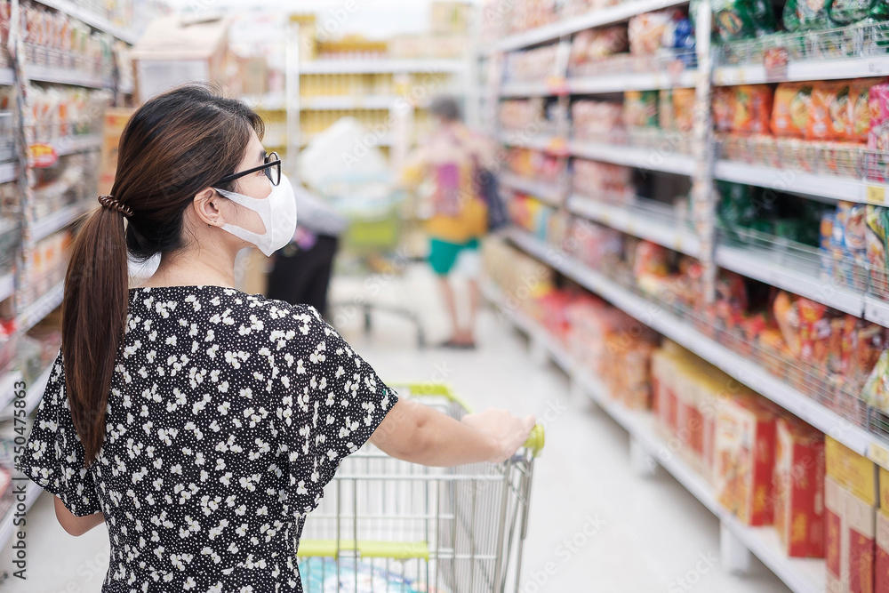 Asian woman wearing protective mask and  shopping in supermarket or grocery, protect coronavirus inflection. social distancing, new normal and life after covid-19 pandemic