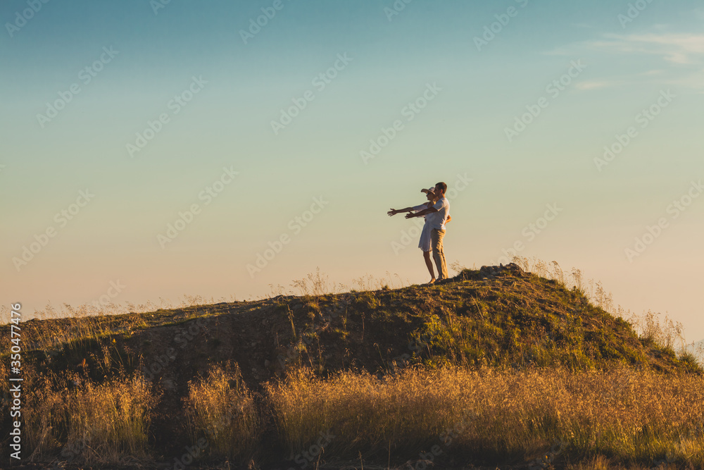 Man and woman on a hill with straightened hands