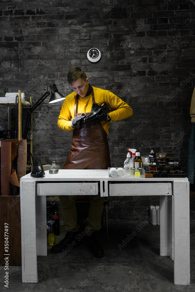A young man is engaged in Shoe repair. Shoe workshop. The photo illustrates a small business A young man is engaged in Shoe repair. Shoe workshop. The photo illustrates a small business