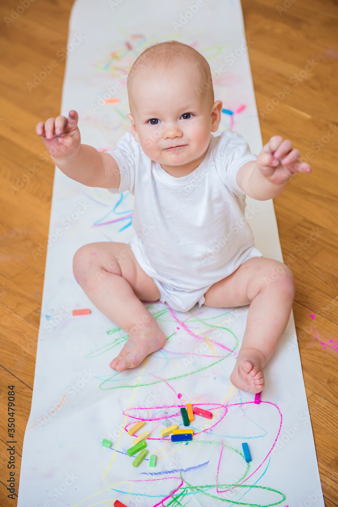 Little cute child with creativity draws with crayons at home on a sheet of white paper. The concept of children's early development of creativity Little cute child with creativity draws with crayons at home on a sheet of white paper. The concept of children's early development of creativity