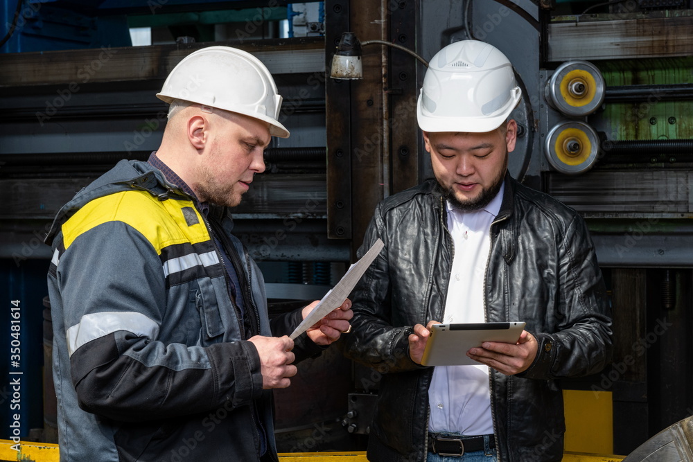 Two young engineers at a modern factory. The photo illustrates new technologies and production. Two young engineers at a modern factory. The photo illustrates new technologies and production.