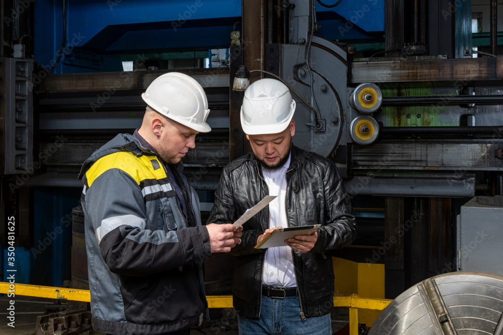 Two young engineers at a modern factory. The photo illustrates new technologies and production. Two young engineers at a modern factory. The photo illustrates new technologies and production.