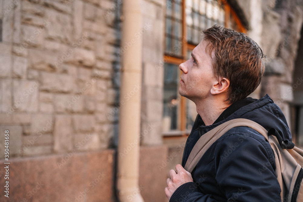 A young man in a jacket walks through the streets of the city, portrait against the background of a beautiful old building, business style A young man in a jacket walks through the streets of the city, portrait against the background of a beautiful old building, business style