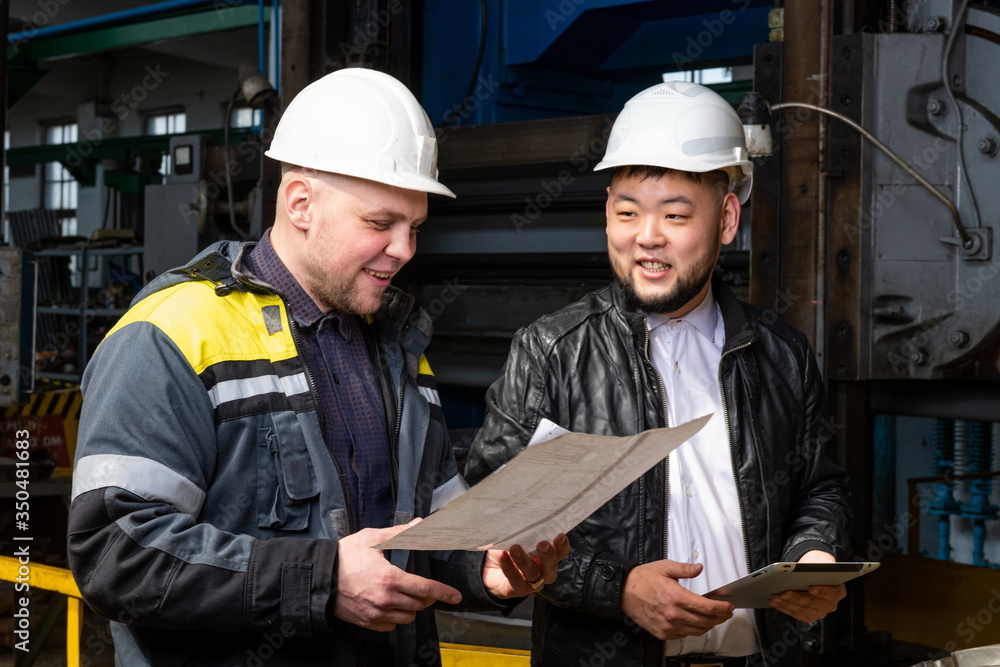 Two young engineers at a modern factory. The photo illustrates new technologies and production. Two young engineers at a modern factory. The photo illustrates new technologies and production.