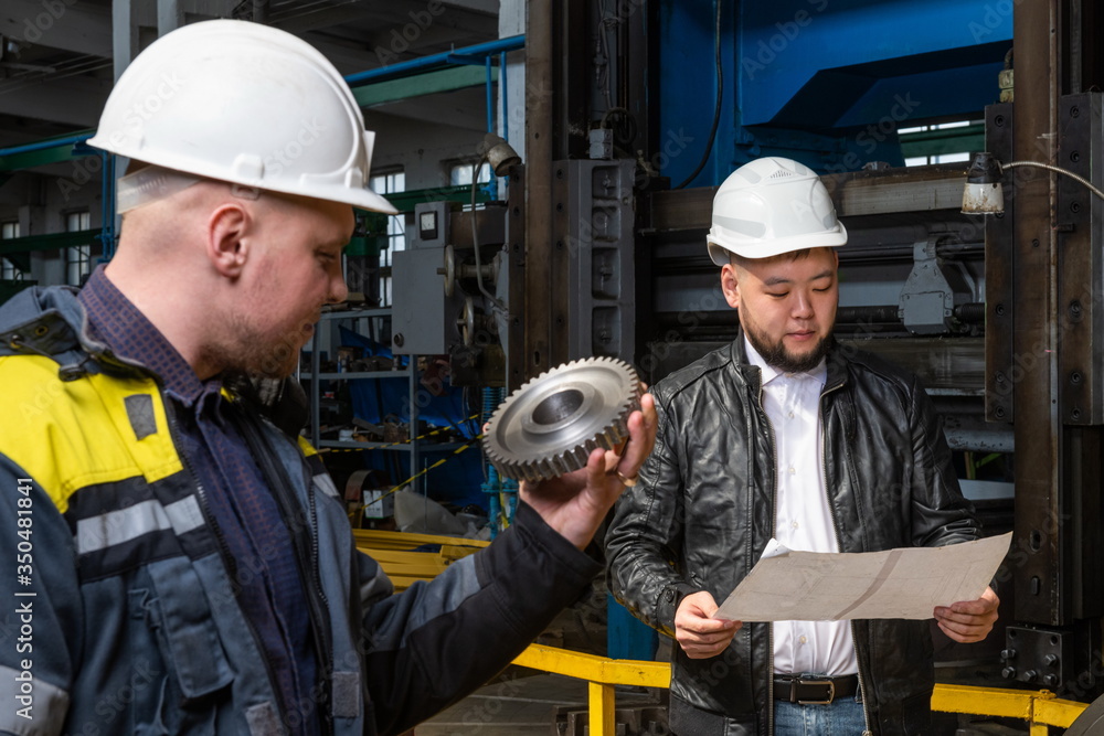 Two young engineers at a modern factory. The photo illustrates new technologies and production. Two young engineers at a modern factory. The photo illustrates new technologies and production.