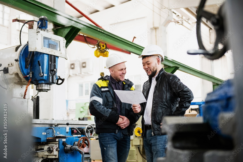 Two young engineers at a modern factory. The photo illustrates new technologies and production. Two young engineers at a modern factory. The photo illustrates new technologies and production.