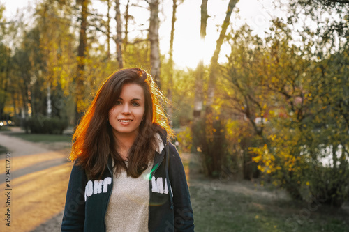 Portrait of a brunette girl in a Park in the sunset rays of the sun, plants are blooming everywhere