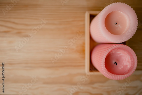 the theme of the Spa. thick pink aroma candles stand on a stand made of natural wood on a wooden table