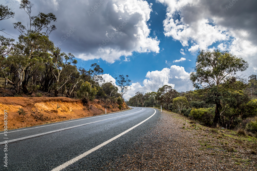 A lonesome road leading through the Kosciuszko national park in the Snowy Mountains, a part of the Australian alps, during a cloudy day in summer.
