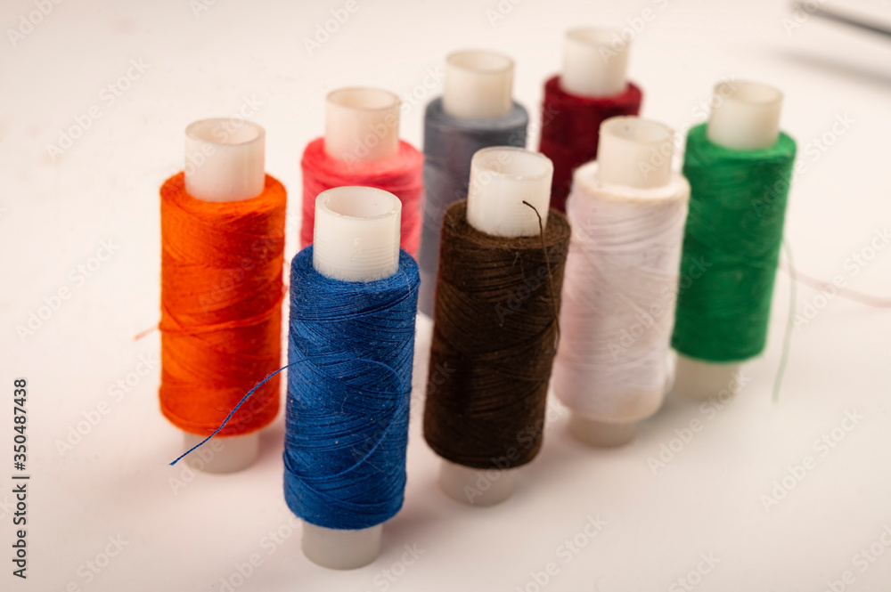 Several reels of multicolored sewing thread on a white background. Close up. Several reels of multicolored sewing thread on a white background. Close up.