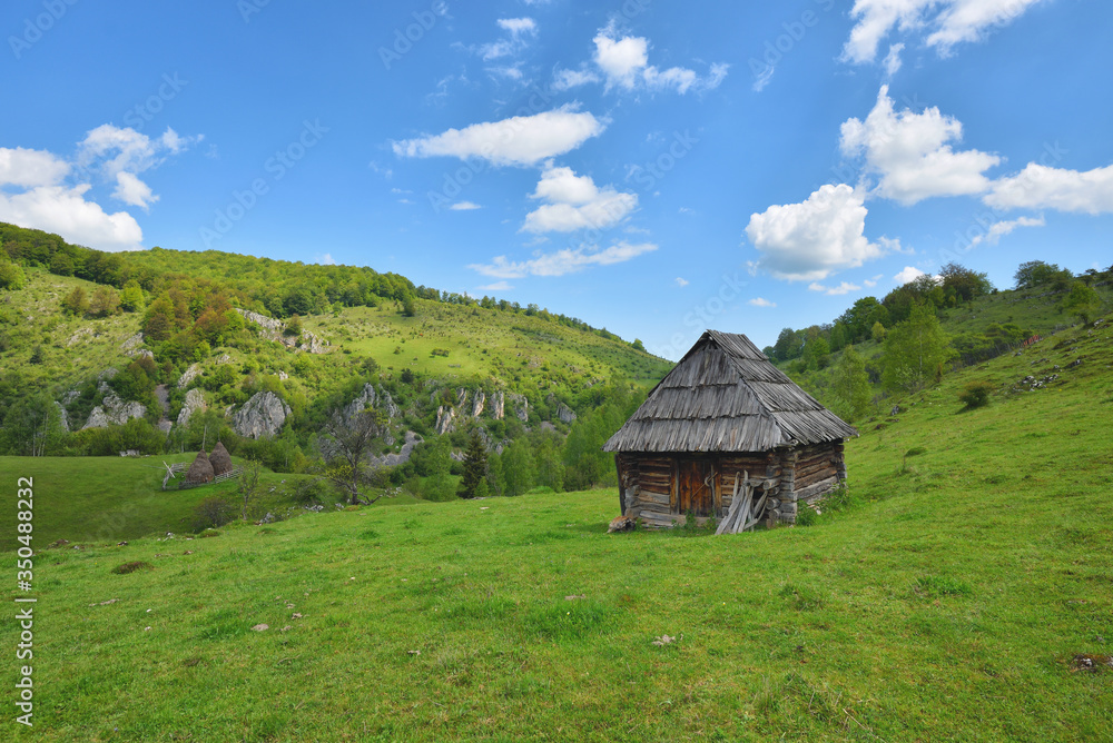Lonely old wood house on a mountain hill with green grass against blue sky Lonely old wood house on a mountain hill with green grass against blue sky