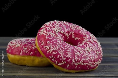 Donuts with pink glaze on a black background close-up.