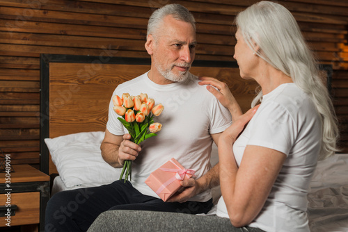 Man surprising wife with flowers and gift