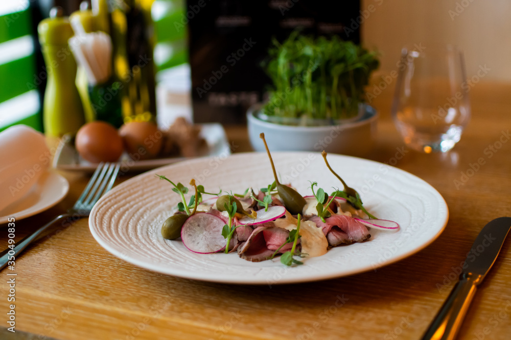 Beef carpaccio on white plate with mustard parmesan Beef carpaccio on white plate with mustard parmesan