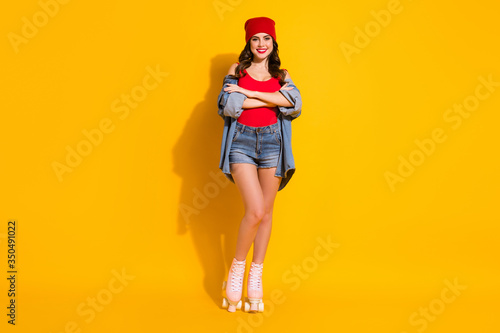 Full size photo of positive cheerful fit street style millennial girl cross hands enjoy roller skates ride rest wear red headwear jeans tank-top isolated over bright color background
