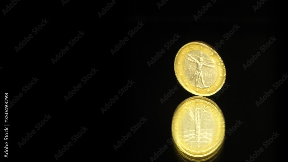 One Euro Coin is rotating on a black mirror One Euro Coin is rotating on a black mirror