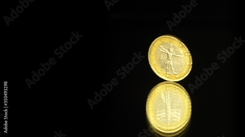 One Euro Coin is rotating on a black mirror