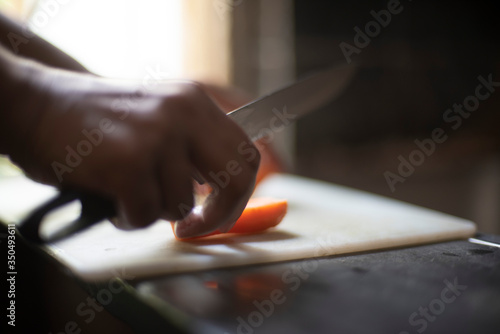 Woman cutting carrot with a knife on a chopping board in an Indian kitchen