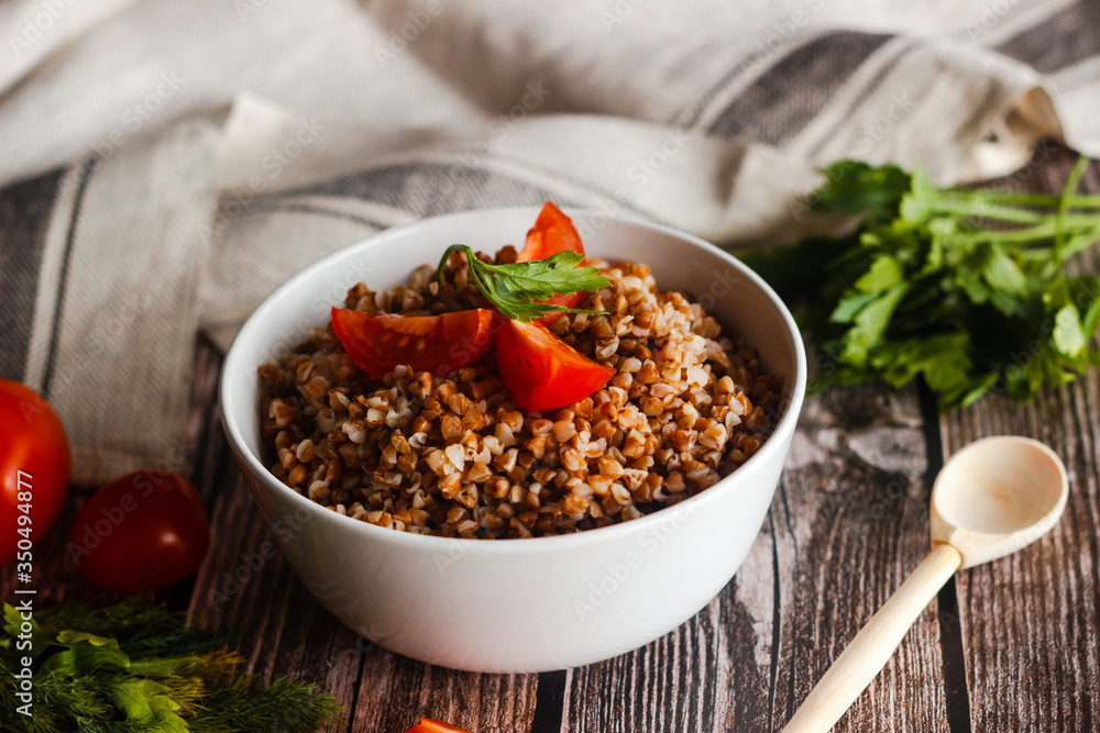 Buckwheat with tomatoes and herbs. The traditional Russian food. Country style. Dish on a wooden table Buckwheat with tomatoes and herbs. The traditional Russian food. Country style. Dish on a wooden table