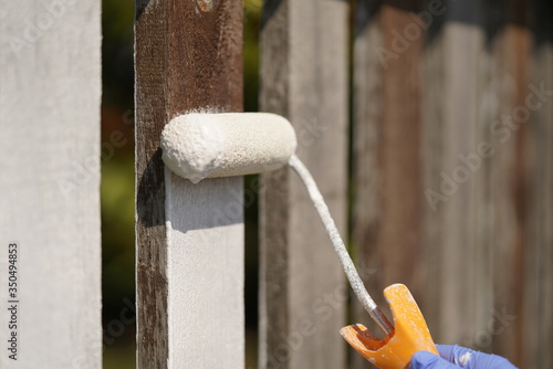 White paint roller on fence.
