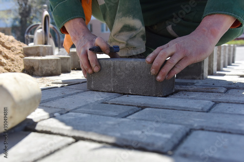A worker puts paving slabs, construction of a pedestrian road.