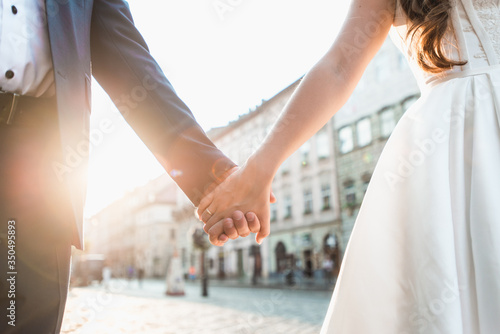 Wedding couple holding hands on sunset background