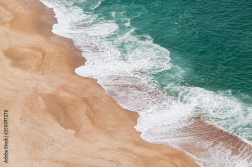 Aerial view of the sandy beach and the big turquoise waves of the Atlantic Ocean. Nazare, Portugal.
