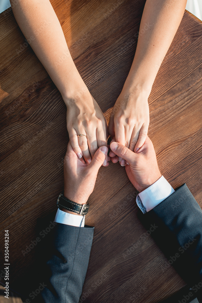 Loving couple siting at the round wooden table, gently holding hands. High angle view