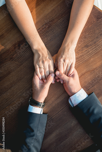 Loving couple siting at the round wooden table, gently holding hands. High angle view