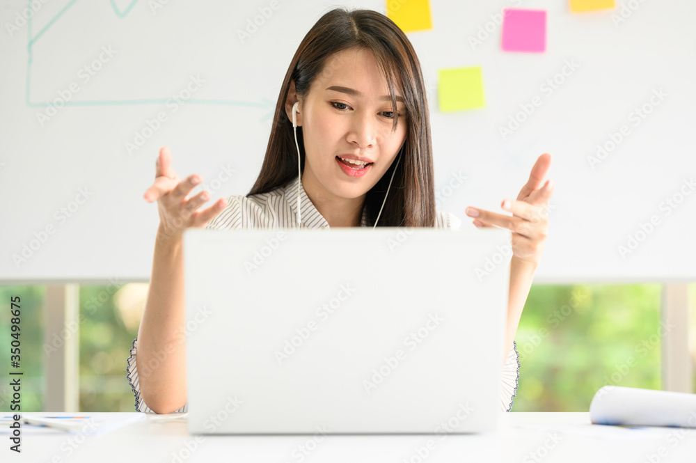 Asian woman having video meeting conference call via laptop. New normal working from home during coronavirus pandemic concept Asian woman having video meeting conference call via laptop. New normal working from home during coronavirus pandemic concept