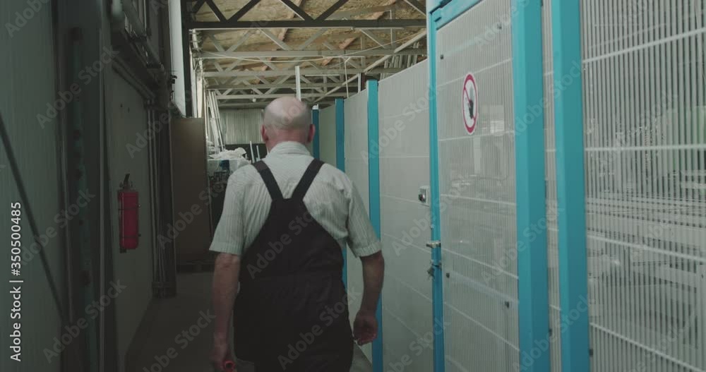 Back view of the electrician with case in hand walking at factory zone Back view of the electrician with case in hand walking at factory zone