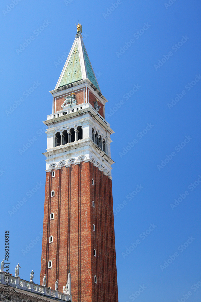 The bell tower of St. Mark's Cathedral against the blue sky on a summer sunny day. Venice, Italy. Photo taken from bottom to top. Vertical format.