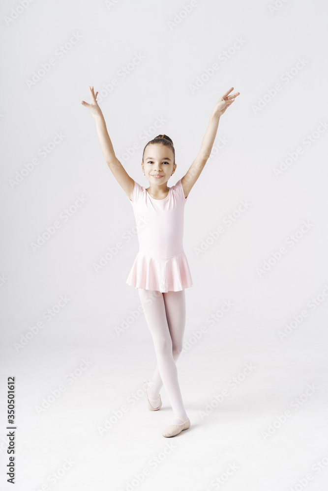 Delicate girl ballerina standing in ballet pose on white background in studio. Kinds personality development concept. Delicate girl ballerina standing in ballet pose on white background in studio. Kinds personality development concept.