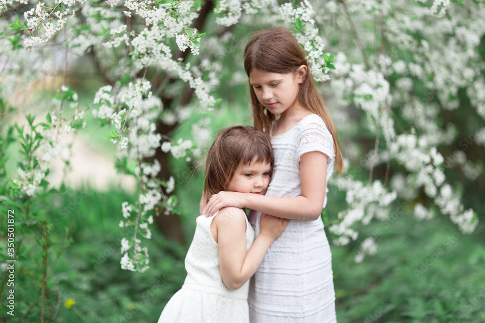 Tender children hugging near flowering tree Tender children hugging near flowering tree
