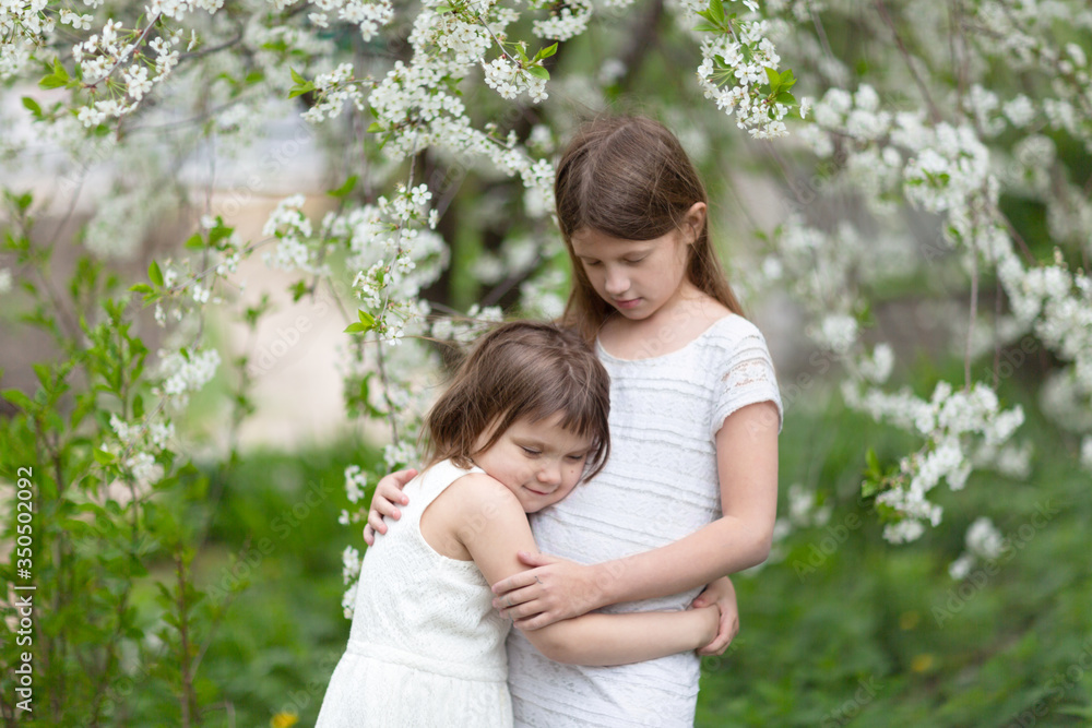 Tender children hugging near flowering tree Tender children hugging near flowering tree