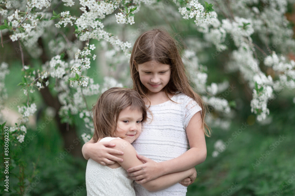 Tender children hugging near flowering tree Tender children hugging near flowering tree