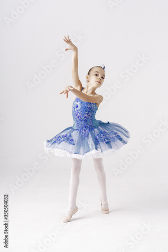 Beautiful preteen girl ballerina wearing a princess dress, winter fairy dancing over white background