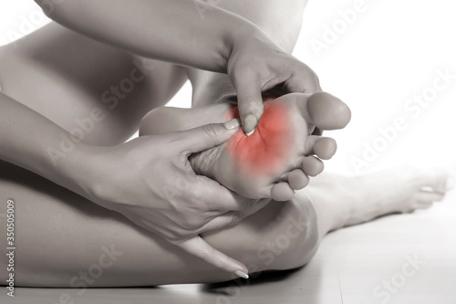 woman massaging her painful foot on white