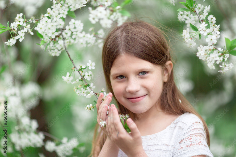 Cute tender Caucasian young girl near a blossoming tree, a child with a blossoming cherry. Concept of spring, freedom and tenderness. Cute tender Caucasian young girl near a blossoming tree, a child with a blossoming cherry. Concept of spring, freedom and tenderness.