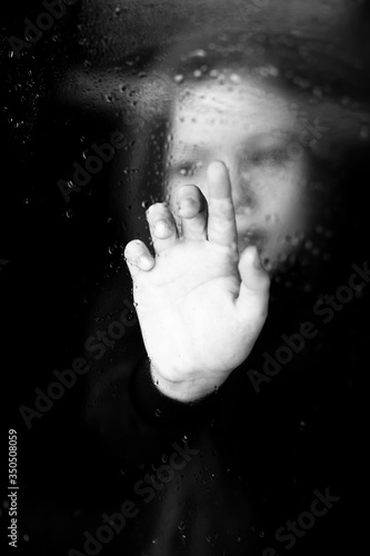 girl stands by the window looks at the rain