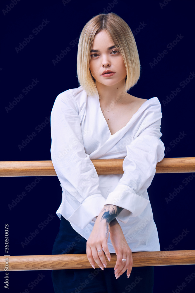 Obraz premium Portrait of a pretty blonde woman standing looking to the camera with crossed hands in white shirt 