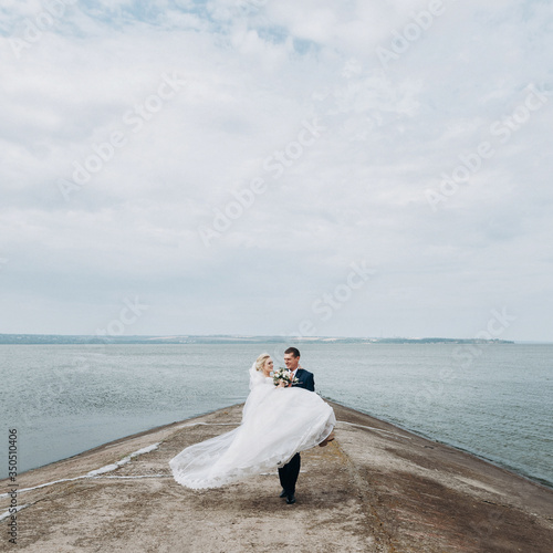 Groom carrying bride on sea background © VlaDee