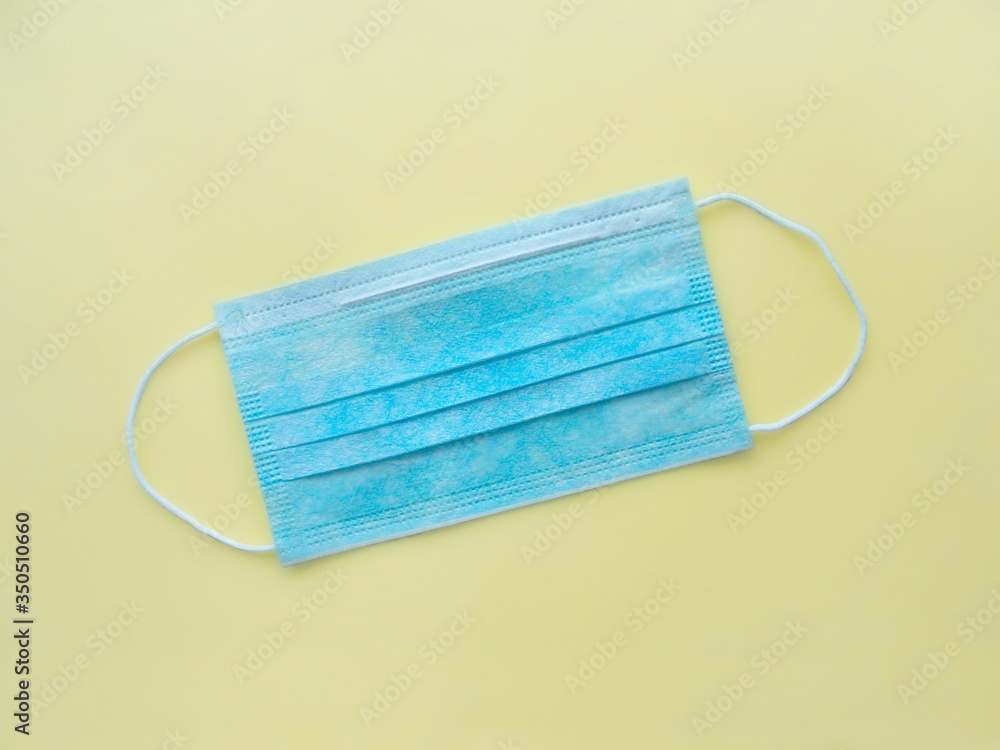 Medical sterile blue protective mask on a pale yellow background Medical sterile blue protective mask on a pale yellow background