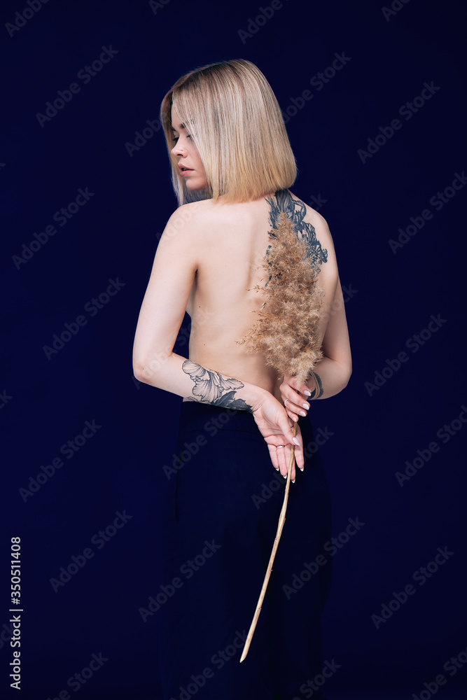 Fototapeta premium Portrait of a pretty blonde woman standing looking to the camera holding a wheat stalk 