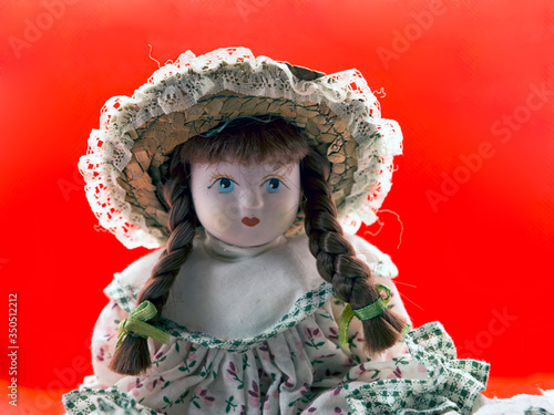 Brunette  porcelain doll portrait she wears vintagedress and braided hair with headdress with princely bearing photo