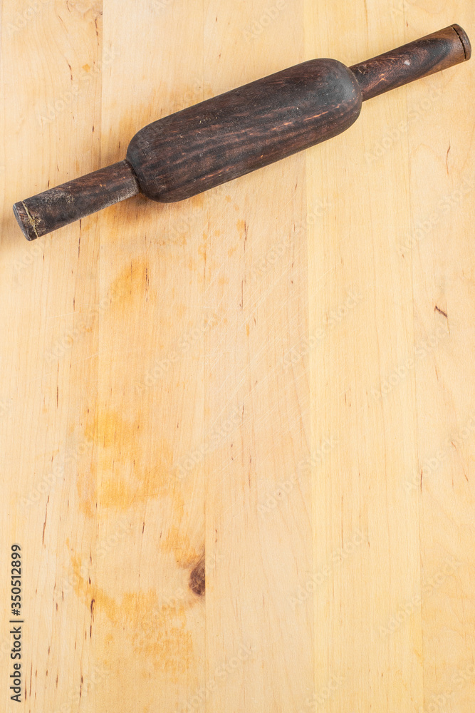 Dark rolling pin on the rough wooden rectangular cutting board background top view. Kitchen equipment. Concept of baking, homemade, hobby, and pastry, copy space.