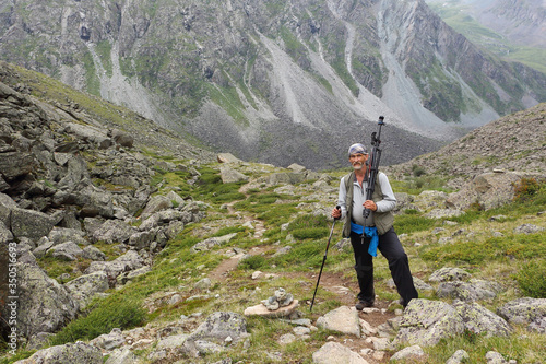 Мan tourist with a tripod and stick climbing the mountains, Natural Park in the Belukha Mountain Area, Russia