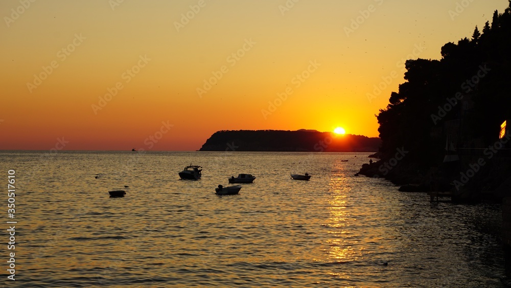 Sun setting over distant island in Dubrovnik, Croatia creating an incredible amber sky and silhouettes 