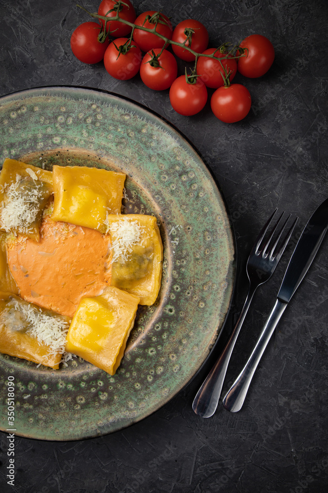 Yellow ravioli with cheese in a plate on a black background Yellow ravioli with cheese in a plate on a black background