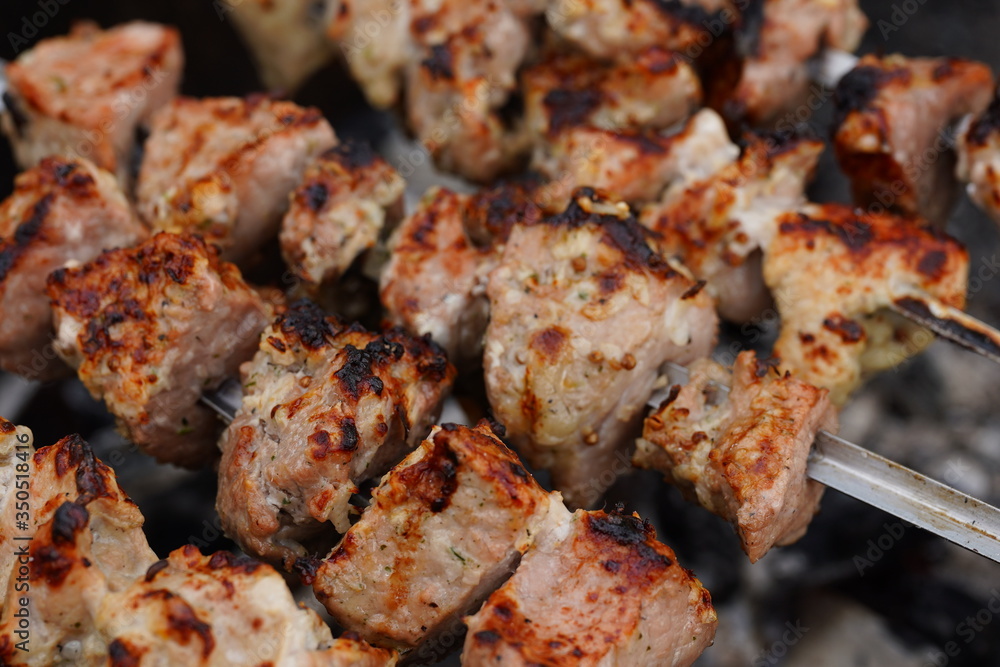Barbecue meat on skewers, beautifully browned meat on the grill. A pork meat on the grill in the spring garden. Cooking shashlik on the mangal in nature. Shashlik cooking on the coals Barbecue meat on skewers, beautifully browned meat on the grill. A pork meat on the grill in the spring garden. Cooking shashlik on the mangal in nature. Shashlik cooking on the coals